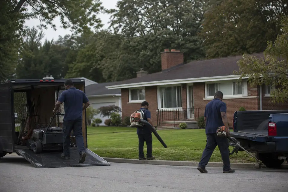 Three crew members unloading commercial mowers from a trailer