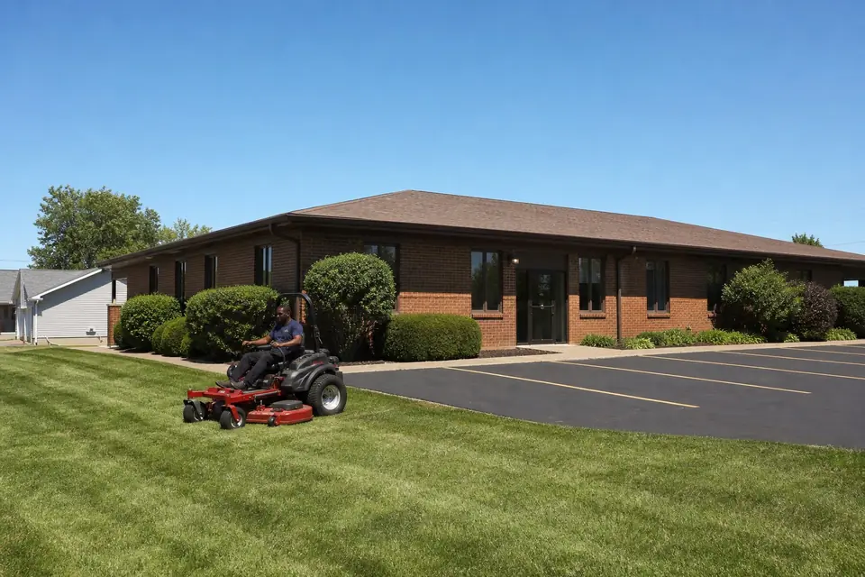 Crew member mowing an office building lawn on a zero-turn mower