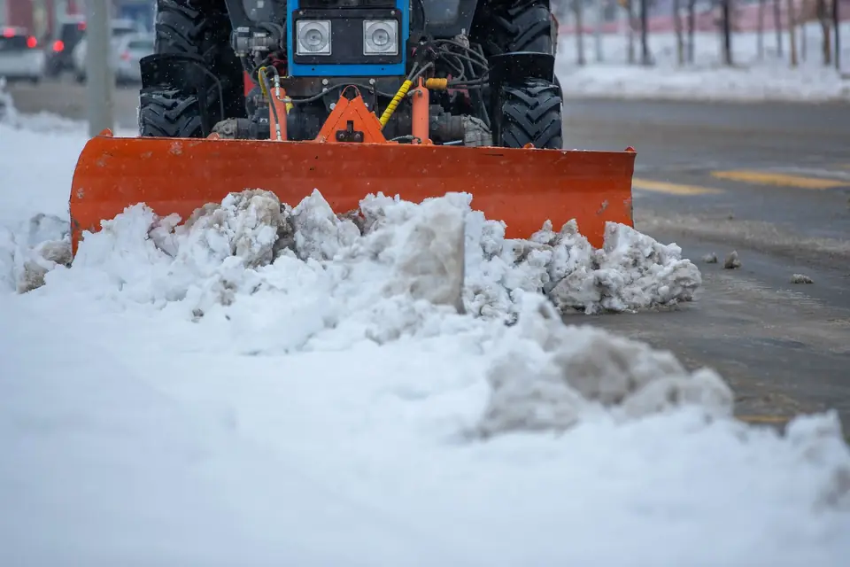 Plow blade pushing a pile of snow off pavement